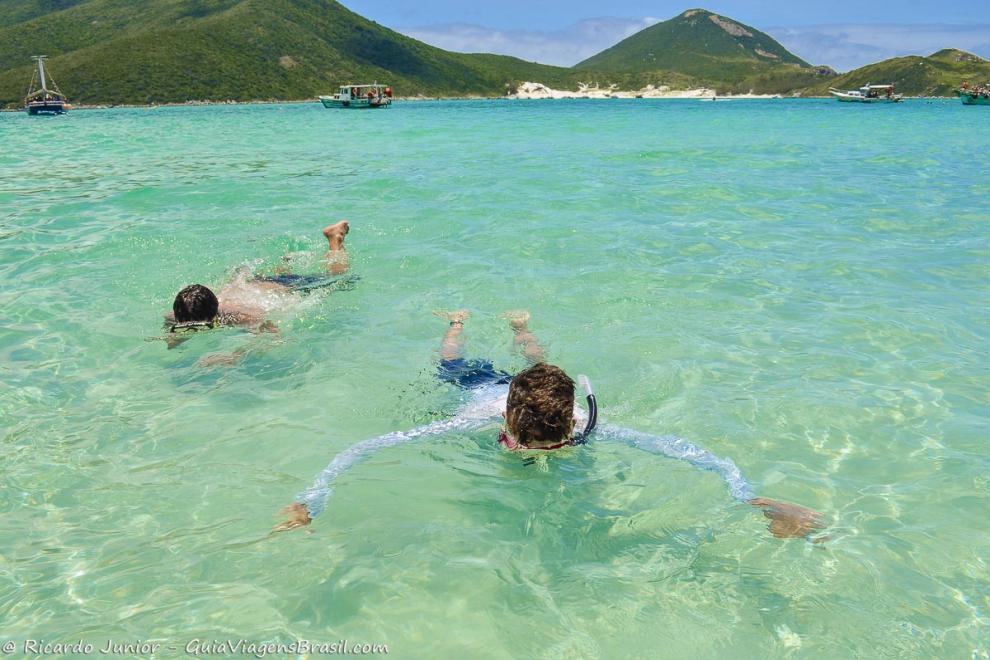 Imagem de dois meninos mergulhando com snorkel na Praia Pontal do Atalaia.